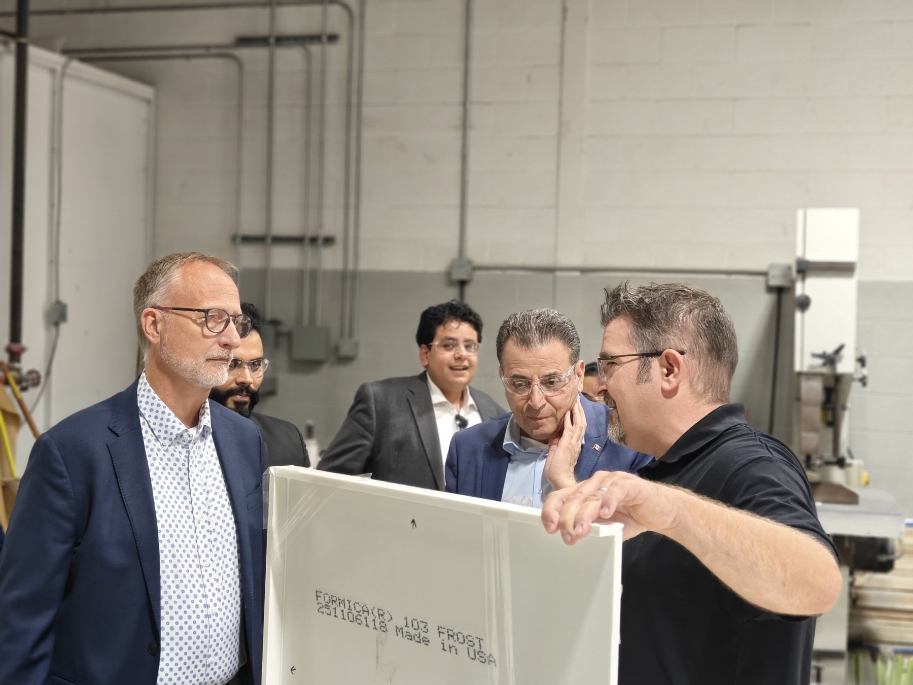 A Sandha representative holds a laminated panel while explaining it to the visiting delegation.